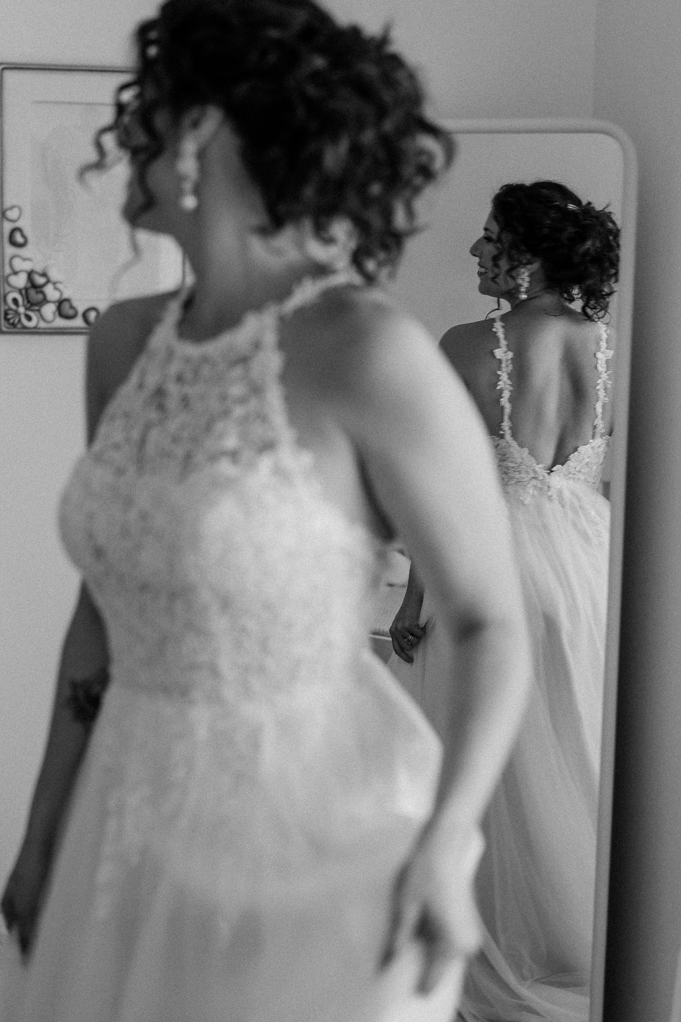 Bride in lace wedding gown viewed from behind in mirror reflection, black and white bridal portrait.
