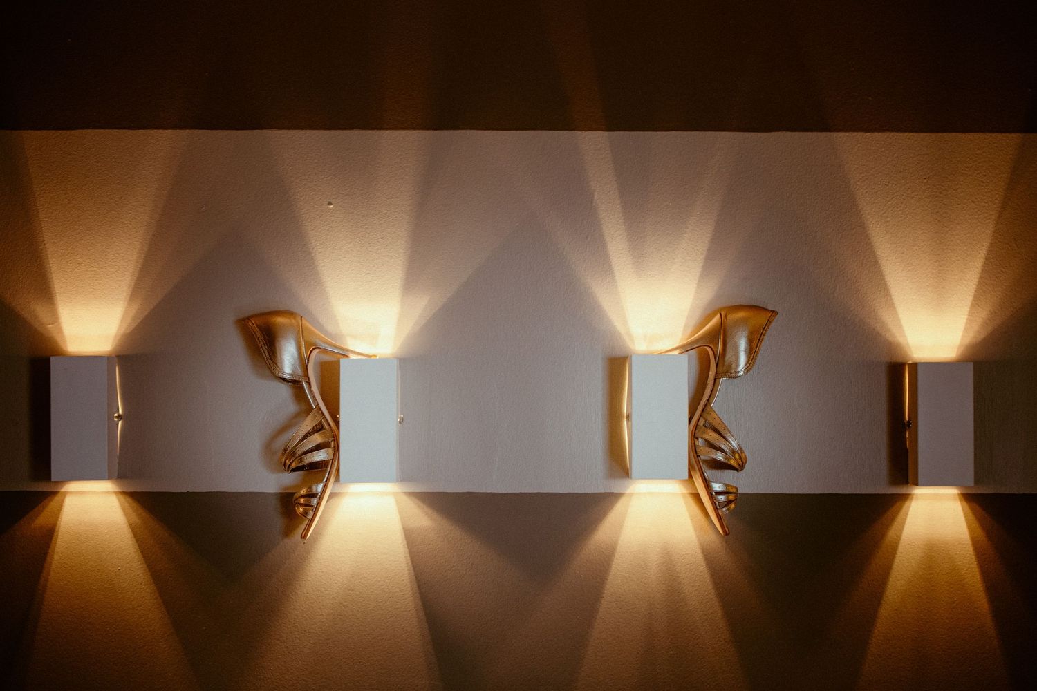 Creative wall sconce installation creating dramatic light patterns against white wall.