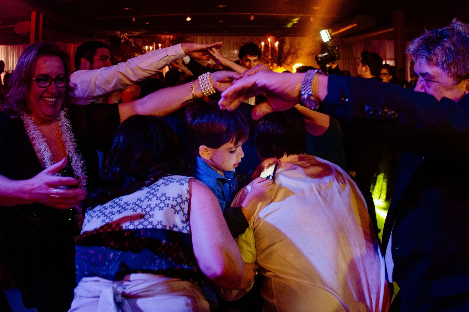 Partygoers dance under colorful lighting at a lively nighttime celebration.