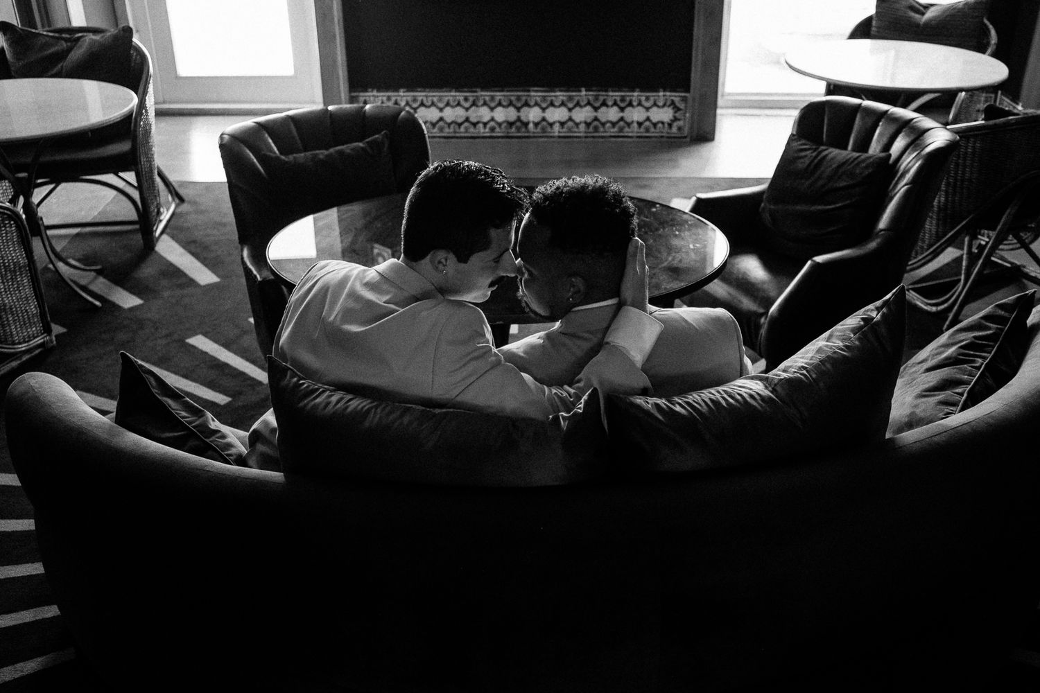 Black and white photo of two people sitting close together on leather chairs in a cozy living room.
