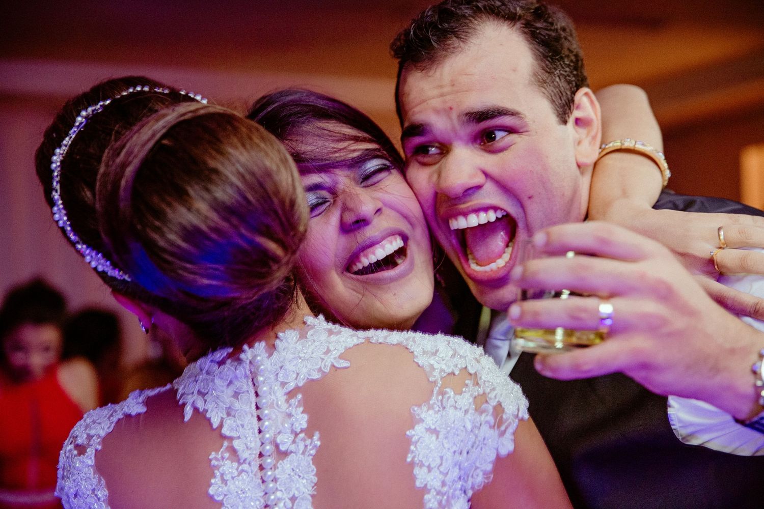 Reception celebration photo with warm lighting and emotional embrace.