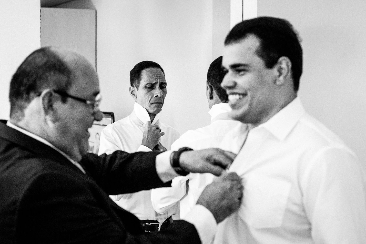 Vintage black and white photo showing two men in formal attire adjusting a tie in an office setting.
