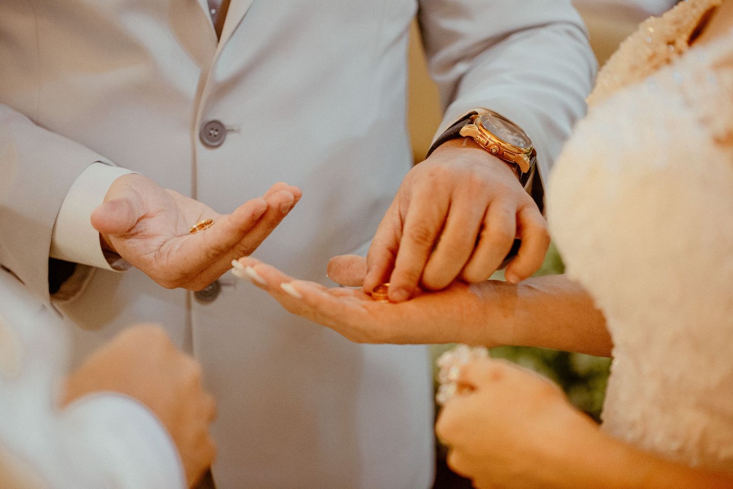 Close-up shot of hands exchanging rings during a wedding ceremony.