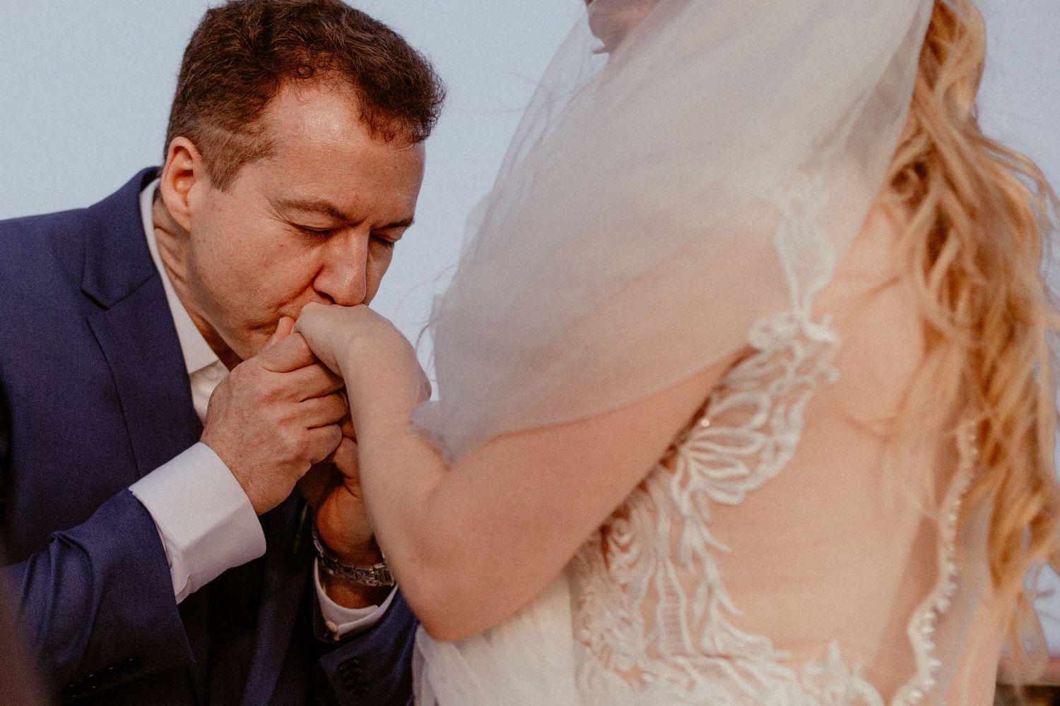 Close-up sequence of newlywed couple sharing their first kiss during romantic outdoor wedding ceremony.