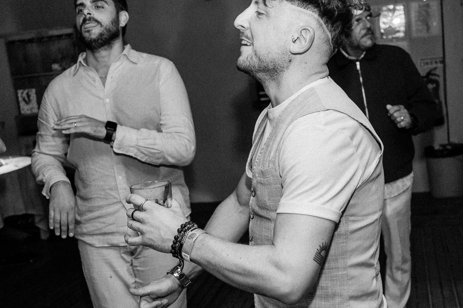 Two men in smart casual attire stand together at an indoor event in black and white photo.