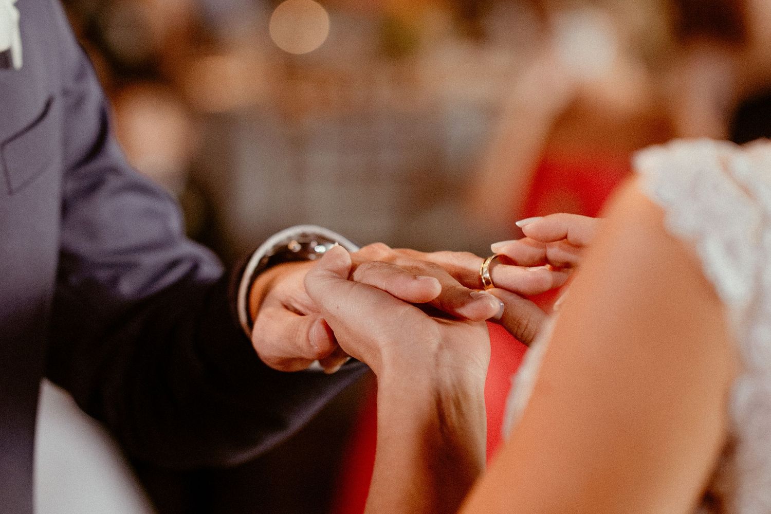 Bride and groom hands exchanging wedding rings during an intimate ceremony.