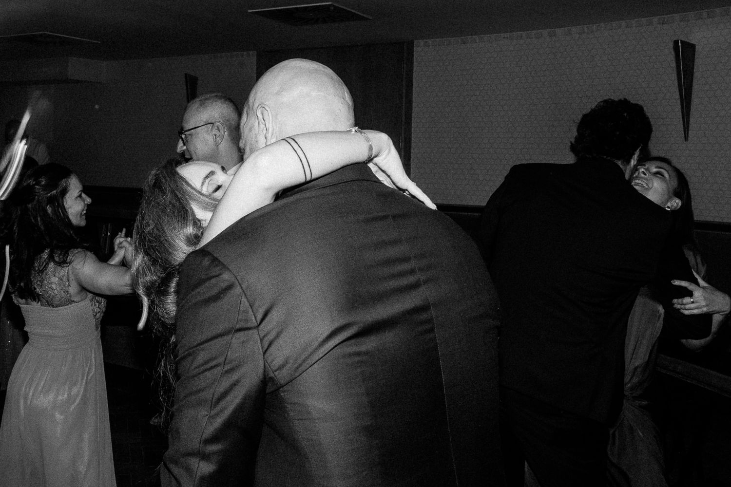 Black and white photo of couples dancing and embracing at a wedding reception party.