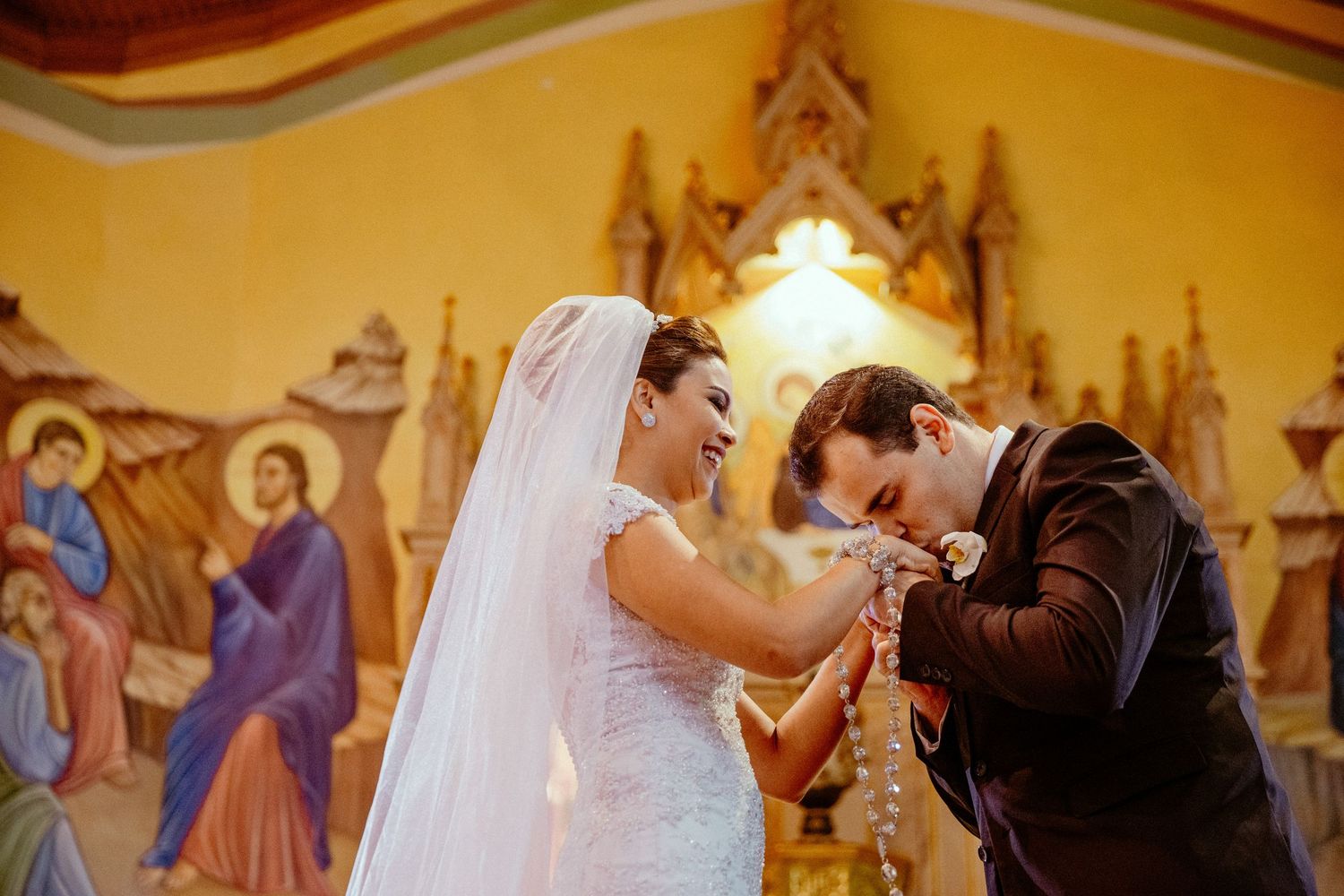 Wedding ceremony inside ornate cathedral with painted murals and golden decorations.