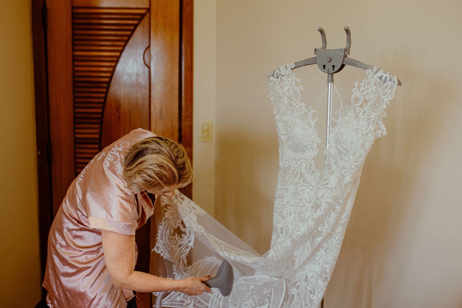 A delicate lace wedding dress being carefully prepared before the ceremony.