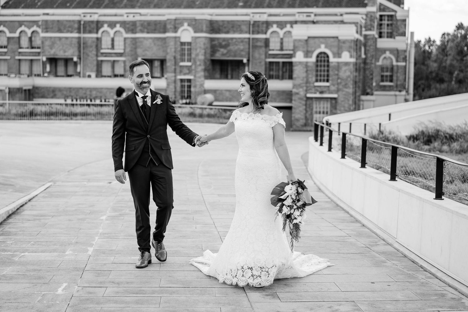Black and white wedding photos show a couple walking together on a brick path outside a historic building.