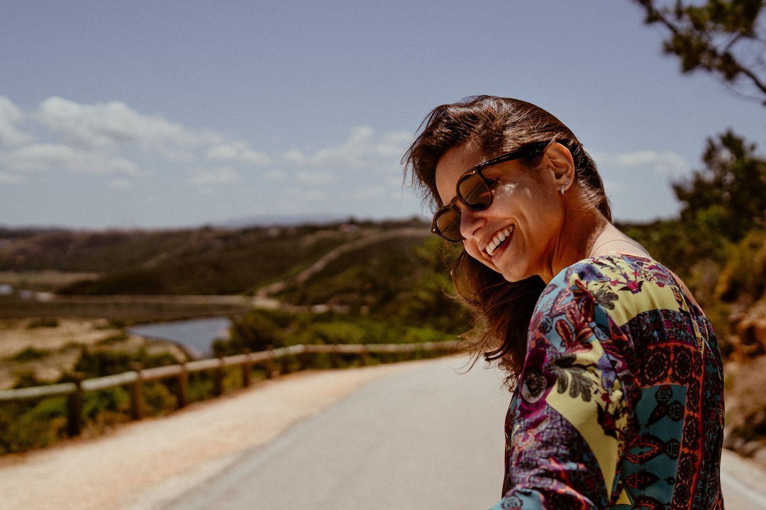 Candid portrait of someone laughing on scenic coastal road with ocean views.