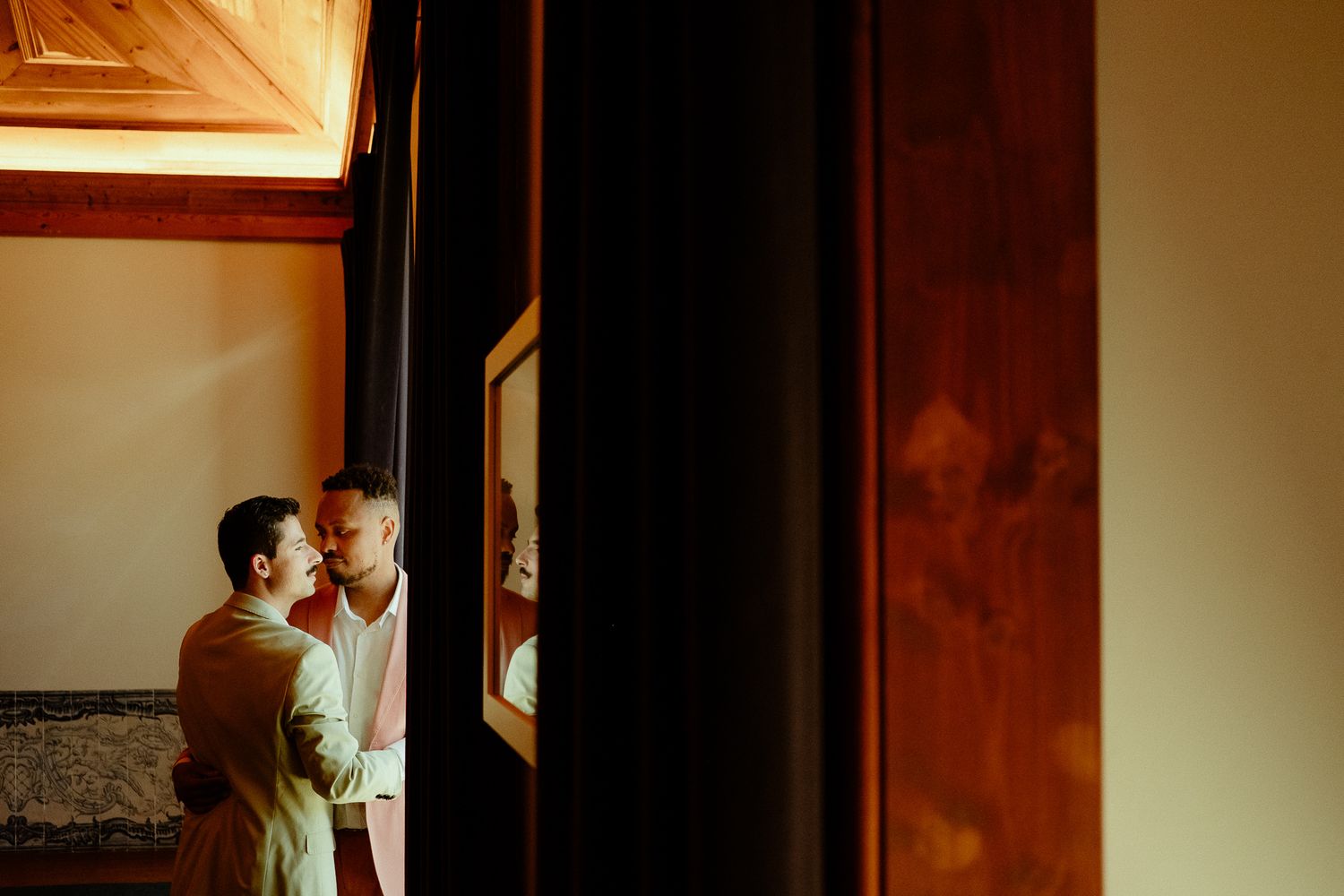Couple sharing a romantic moment in a warmly lit elegant interior with wooden accents and framed artwork.