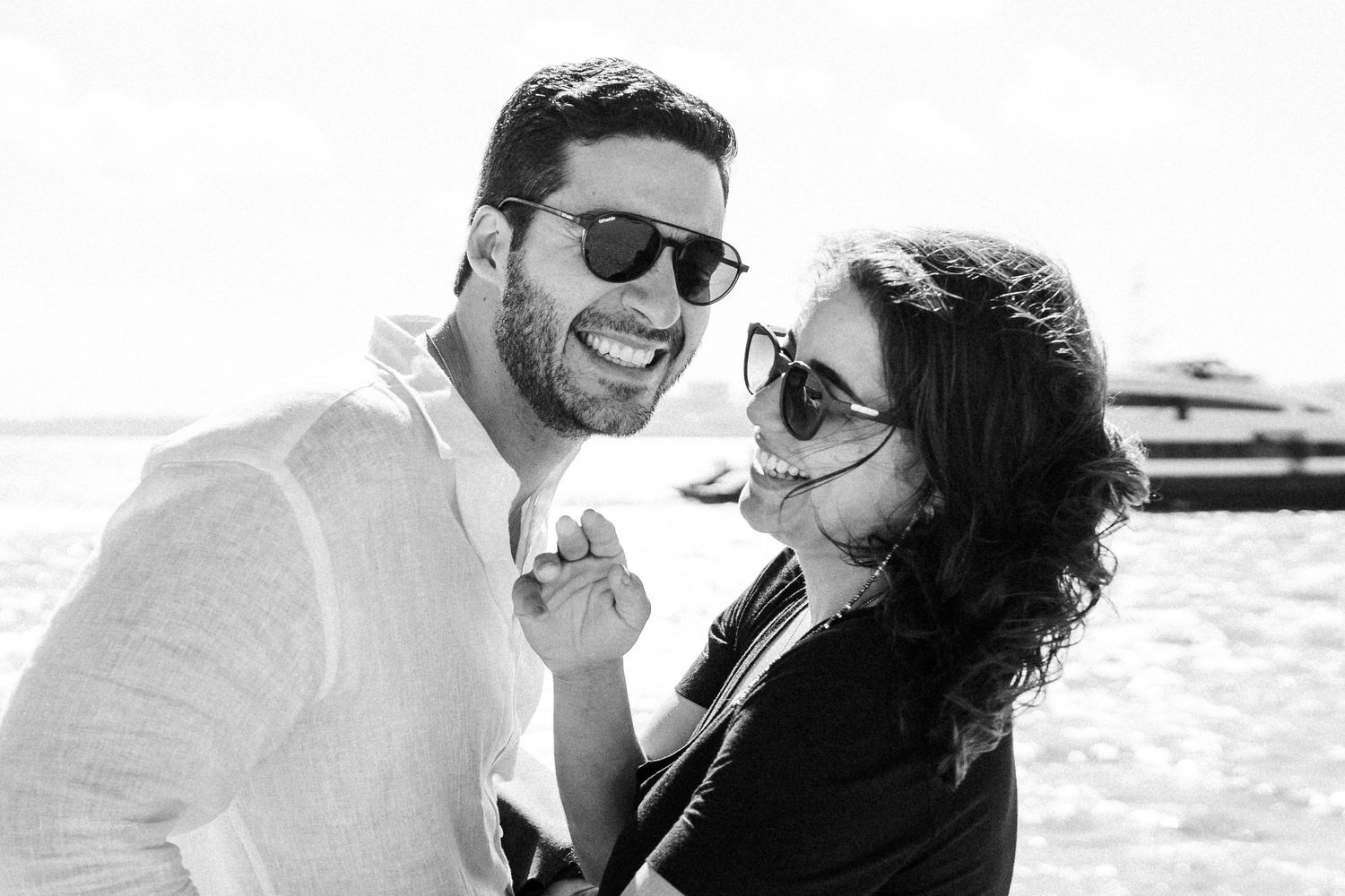 Two people in white outfits share a romantic moment by the ocean during sunset.