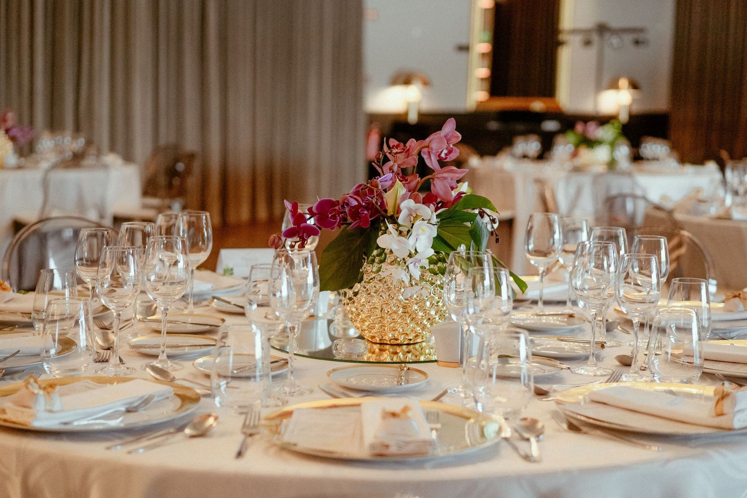 Elegant table settings with crystal glasses and white linens at an upscale banquet reception.