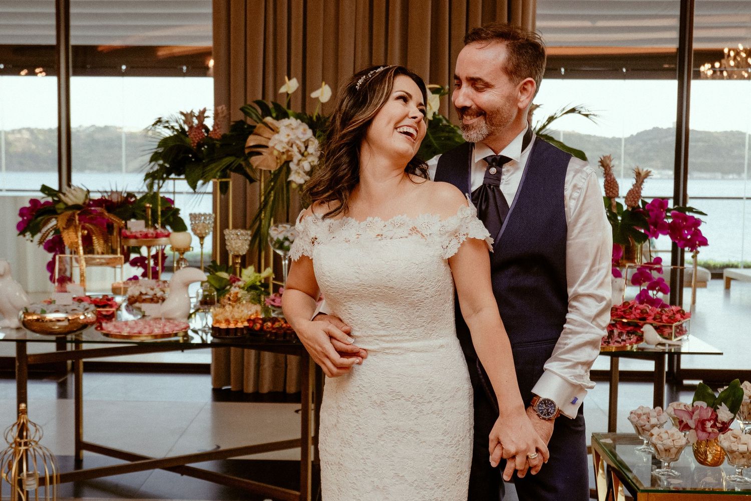 Romantic wedding couple shares intimate moments in an elegant venue decorated with vibrant pink floral arrangements.