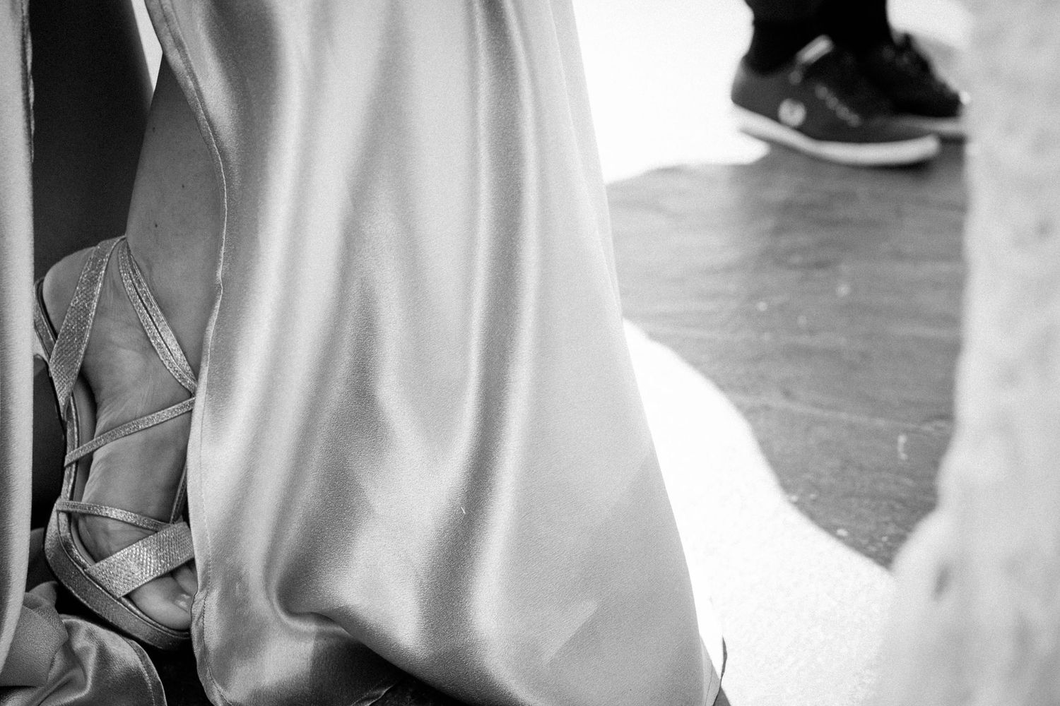 A bride in a flowing white wedding dress walks down a hallway with natural light streaming through windows.