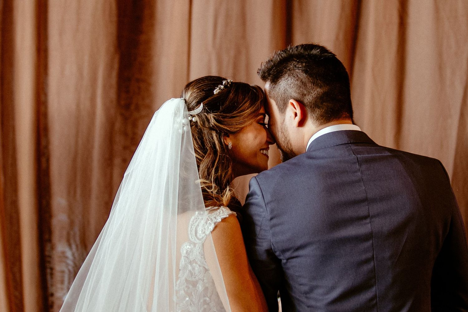 A tender wedding moment as a couple shares an intimate moment with the bride wearing a flowing white veil.