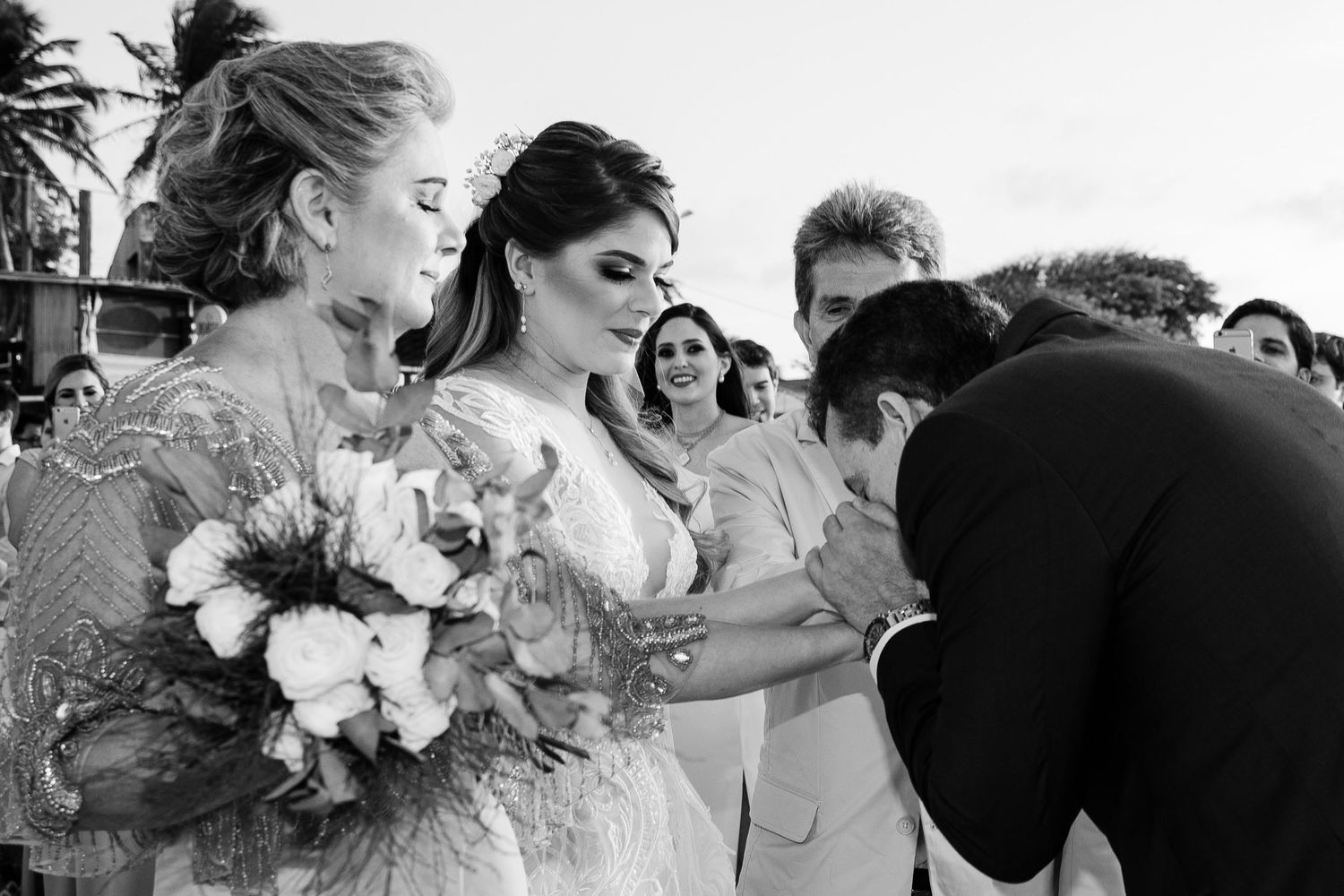 Black and white wedding celebration photos showing groups of people hugging and embracing during emotional moments.