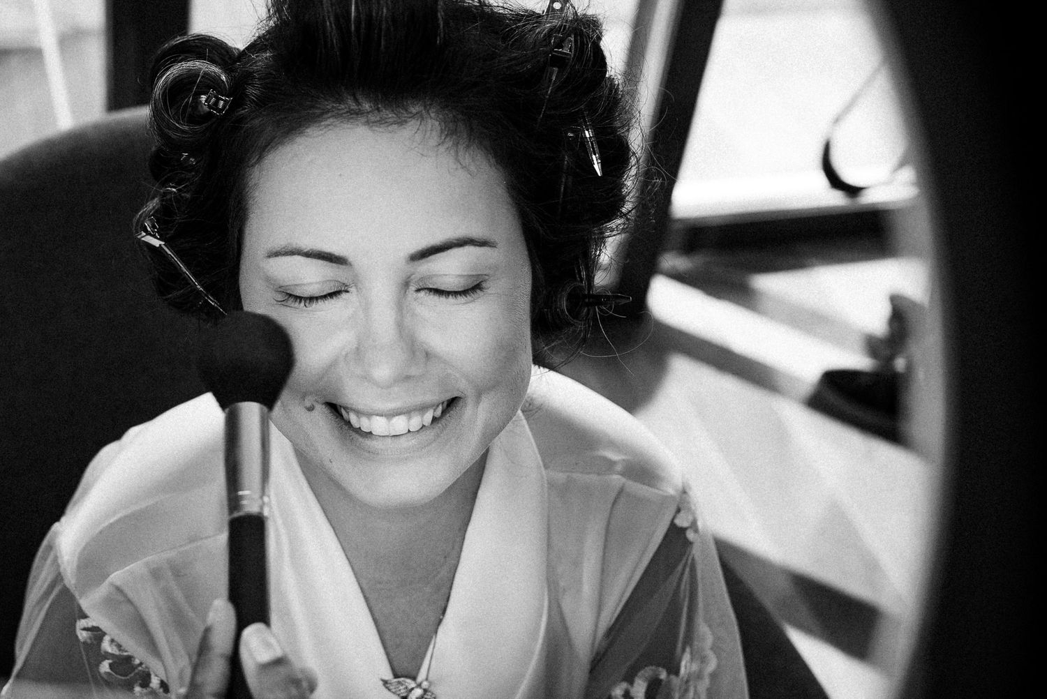 A series of five black and white portraits showing a bride smiling and laughing in different candid moments.
