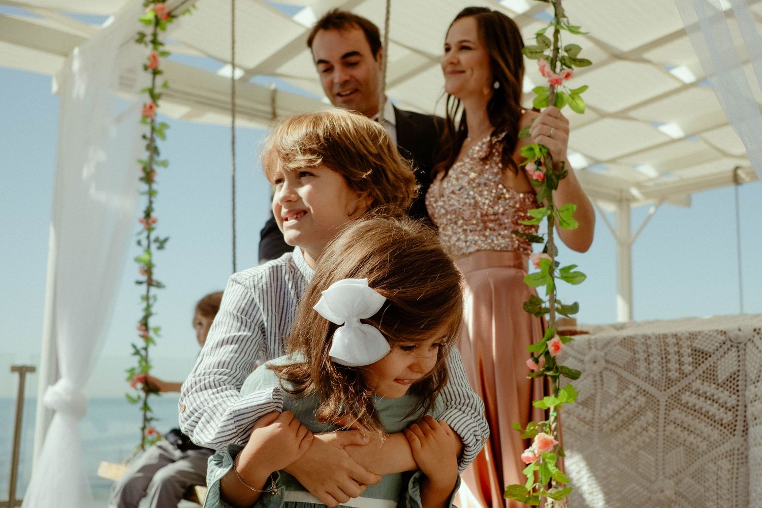 An outdoor wedding ceremony setup with white chairs and floral decorations in a bright greenhouse-style venue.