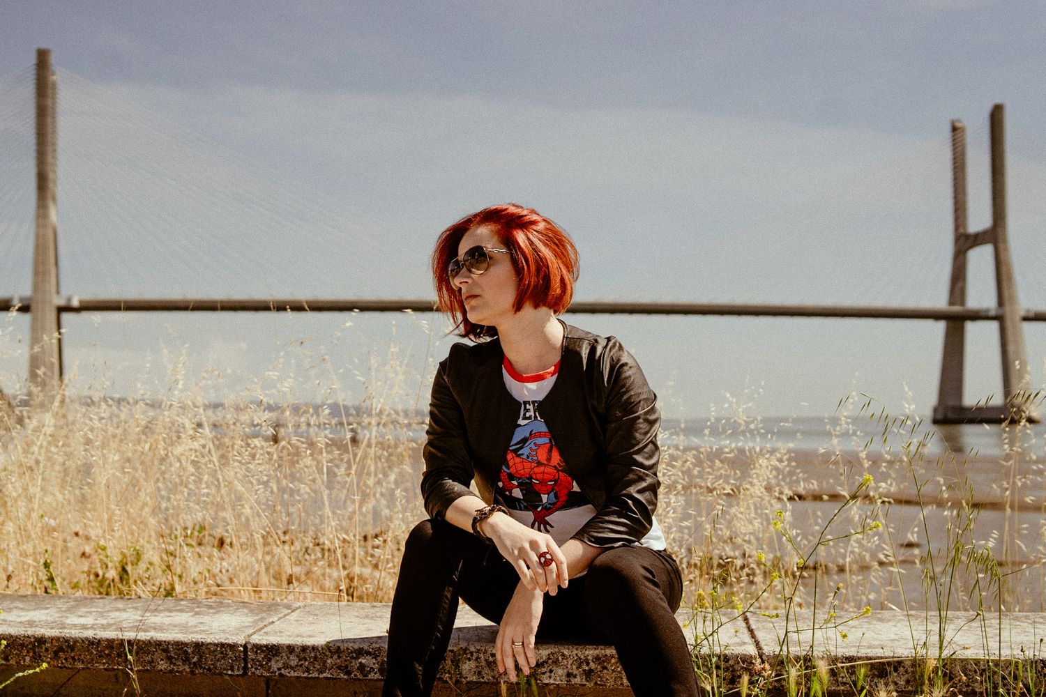 Casual portrait by a bridge with red hair catching the sunlight.
