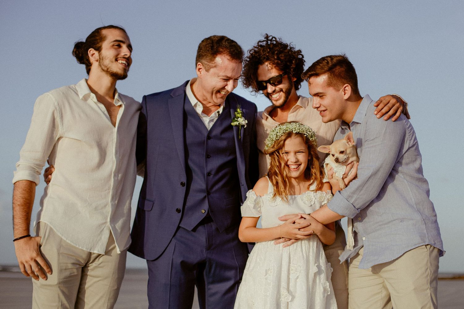 A happy group in casual and formal attire share a joyful moment together at sunset outdoors.