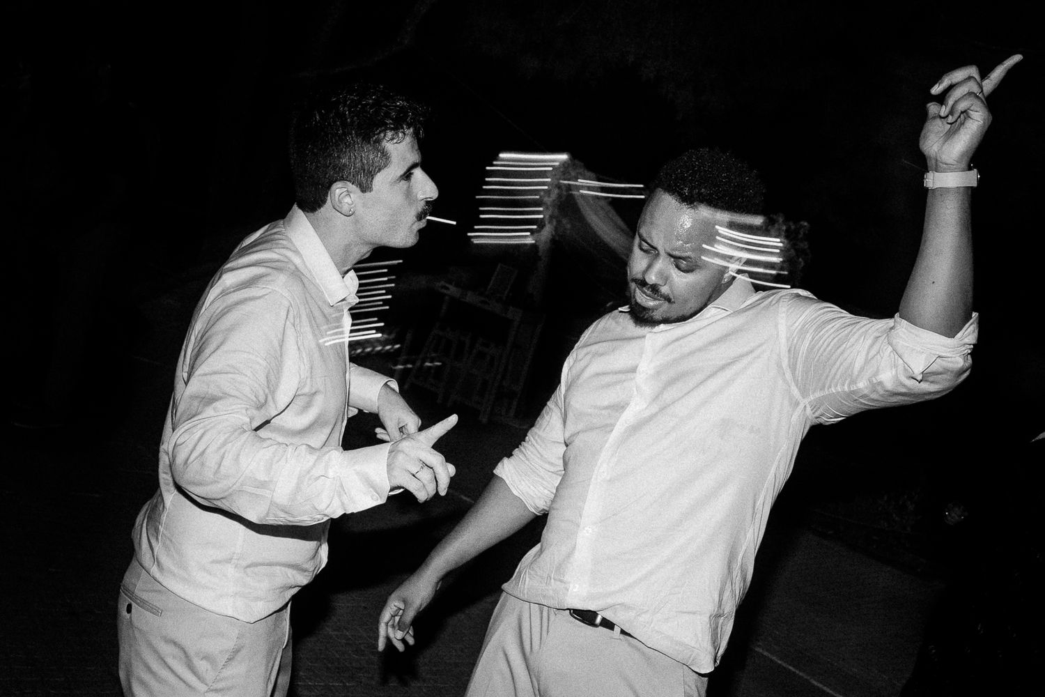 Two men dancing energetically at a party in black and white photo.