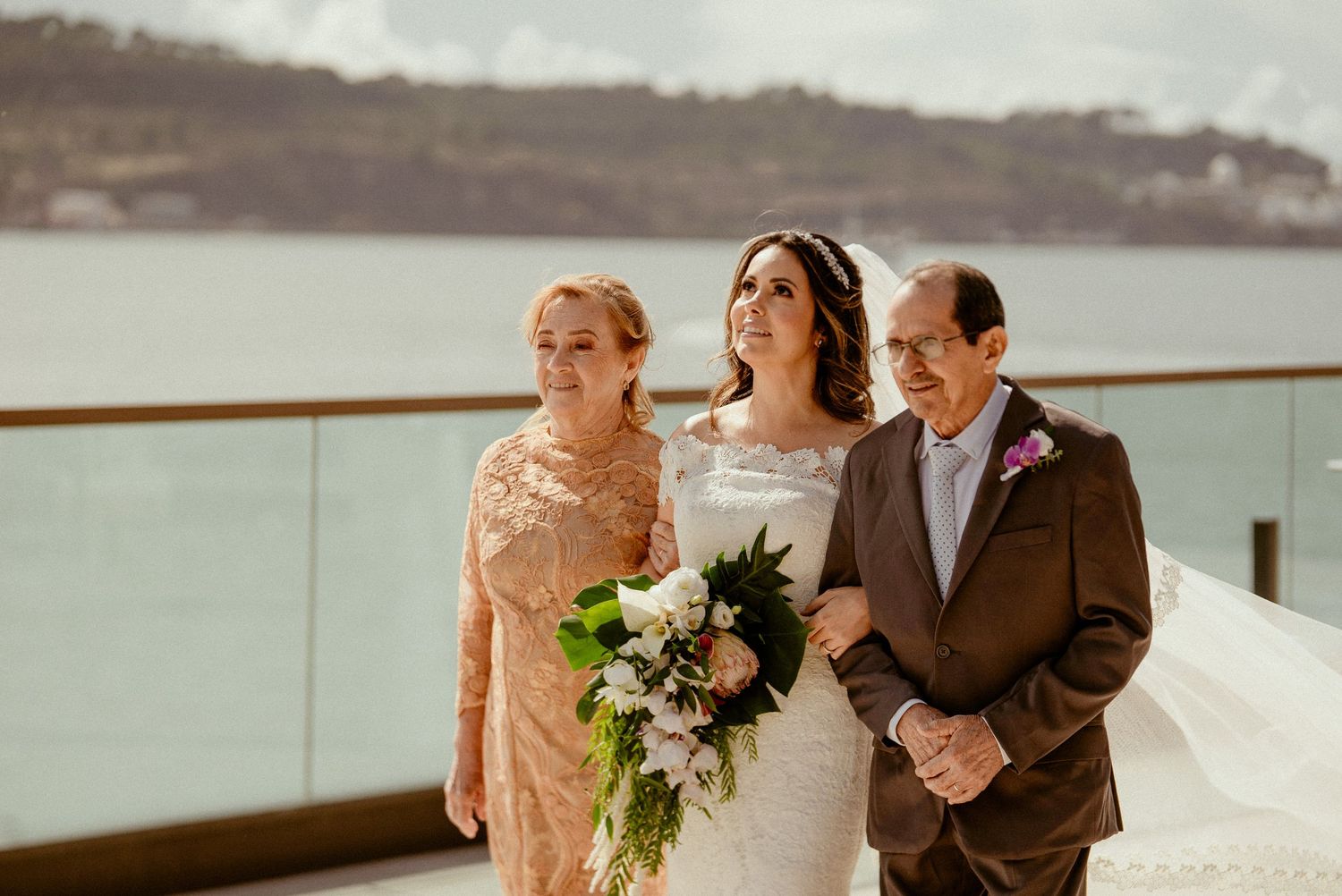 Group of wedding guests celebrate with champagne at elegant venue by waterfront during golden hour.