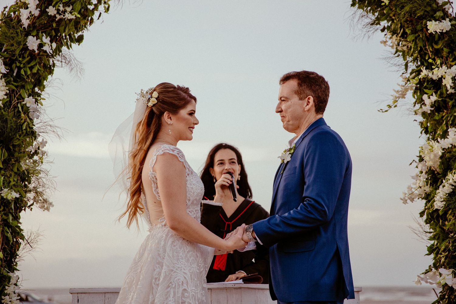 An intimate beachside wedding ceremony with guests gathered around under tropical trees.
