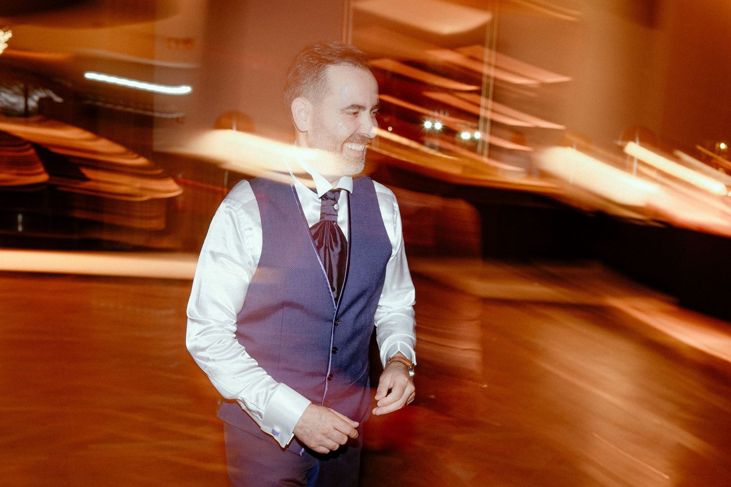 Person in formal attire walking through venue with motion blur light trails creating dynamic effect.