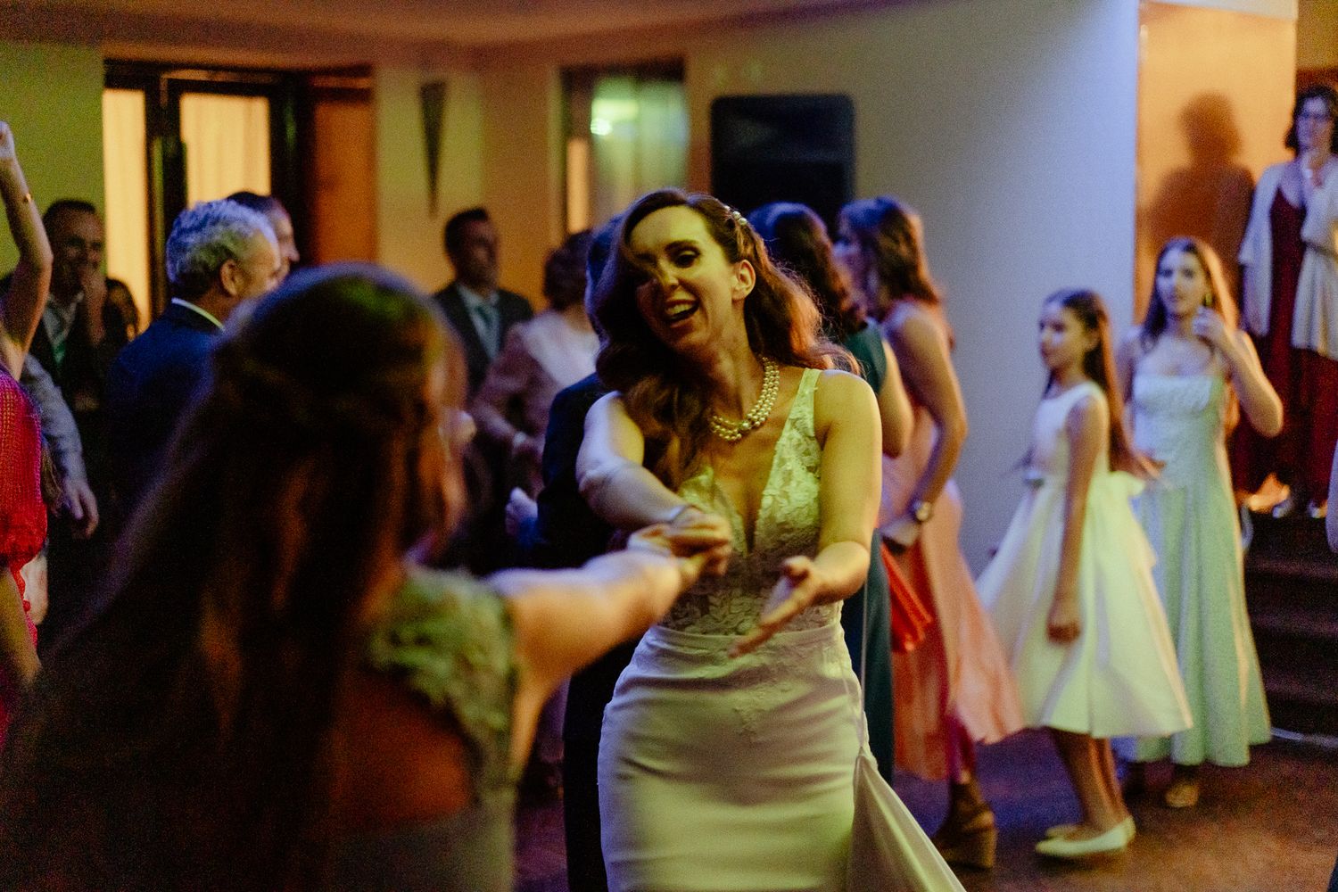 Women in elegant dresses dancing joyfully at a wedding reception party.