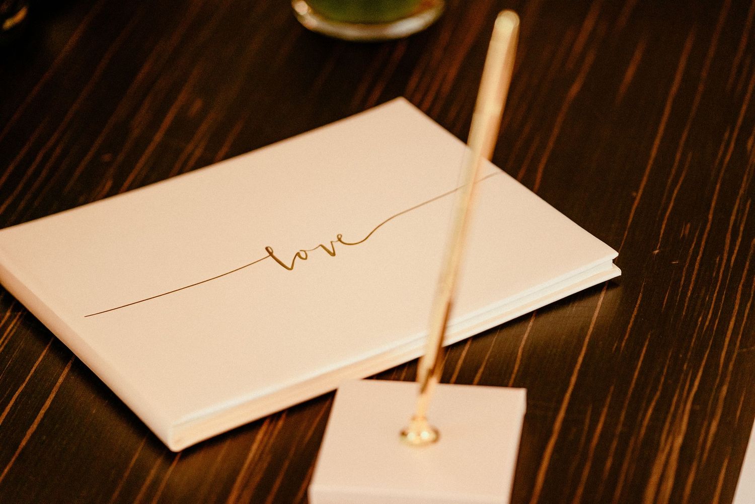 Gold wedding rings and handwritten love note on dark wooden surface create romantic wedding detail shot.