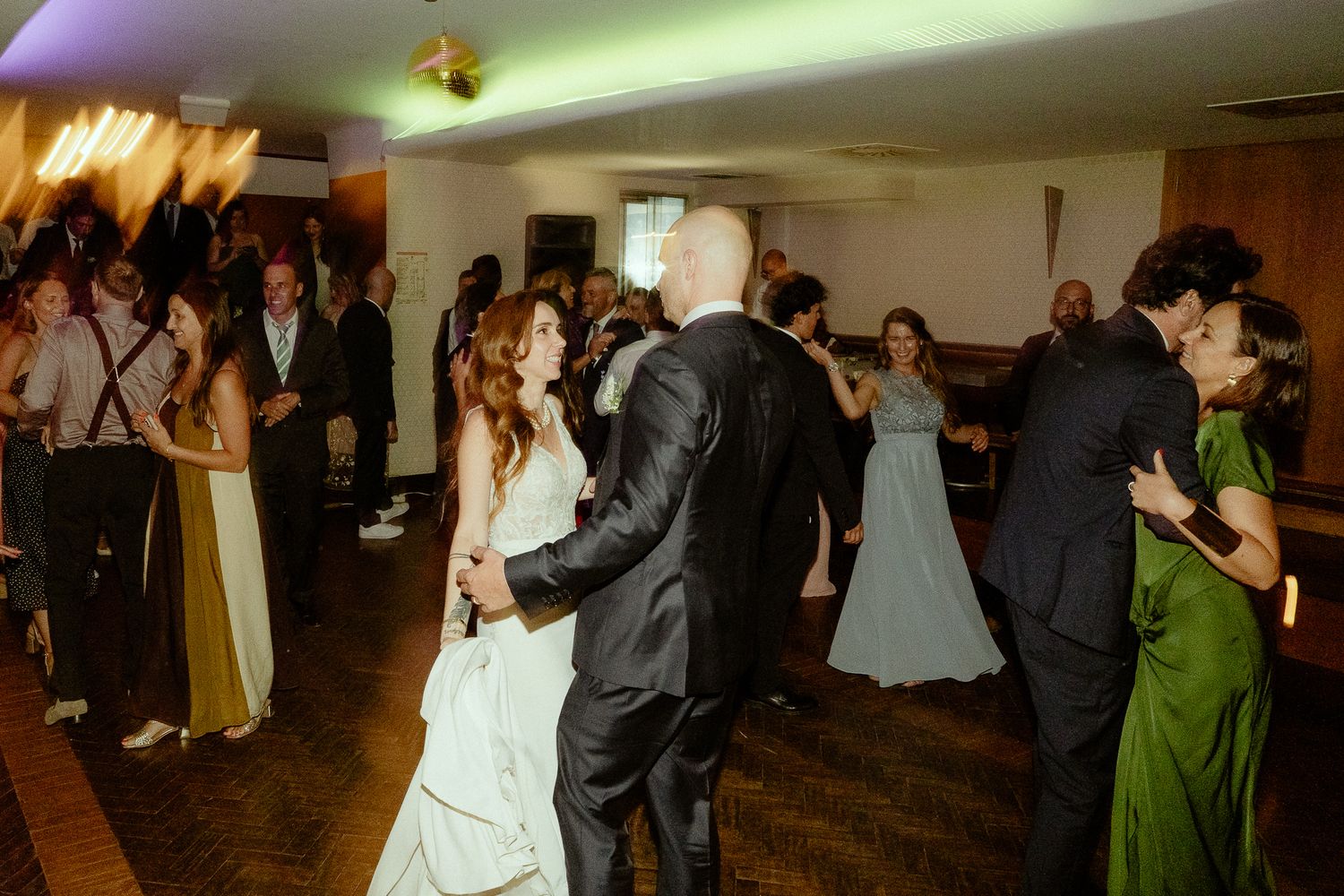 Bride and groom share first dance surrounded by guests at elegant wedding reception venue.