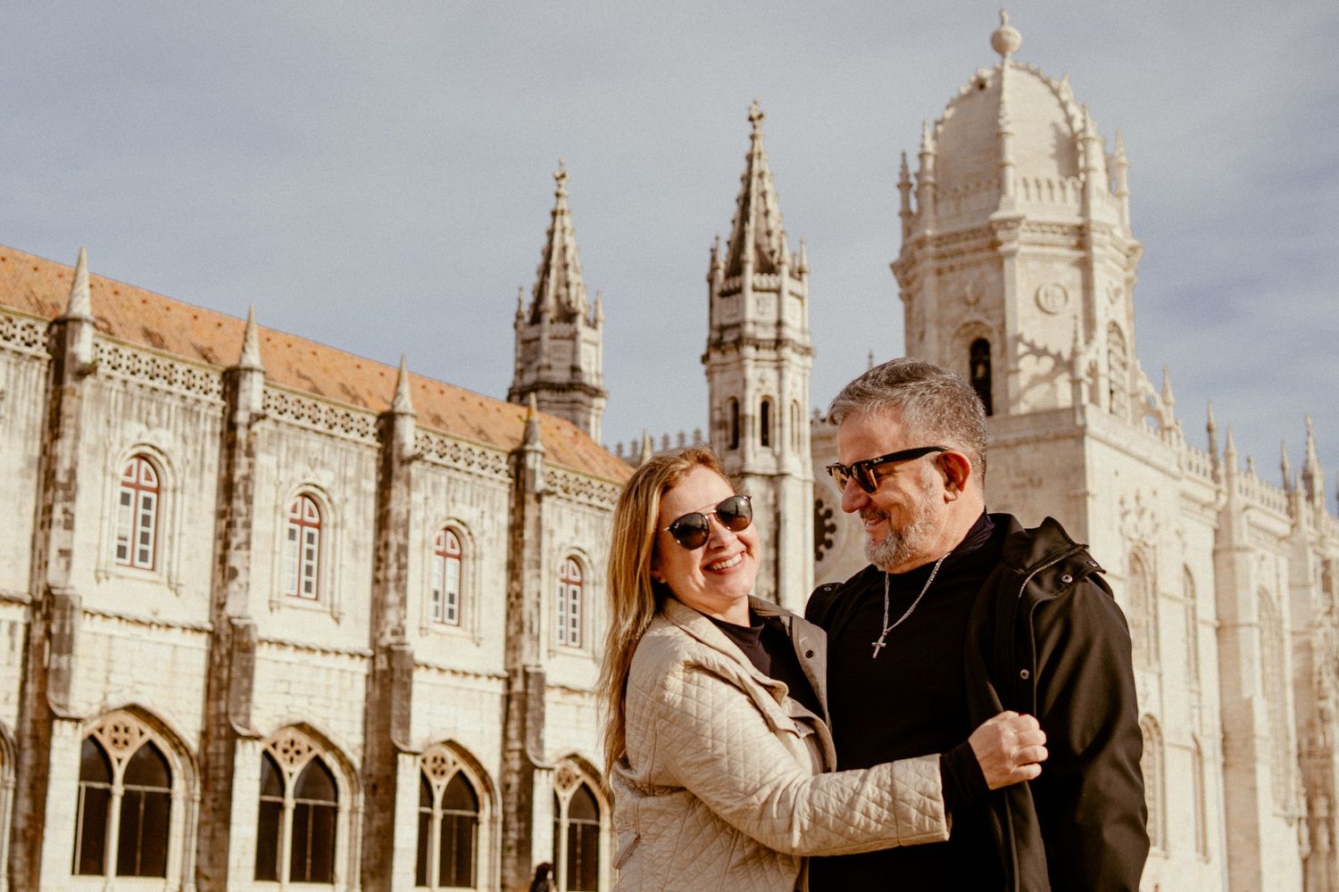Couple posing together against the historic Jeronimos Monastery facade in Lisbon.