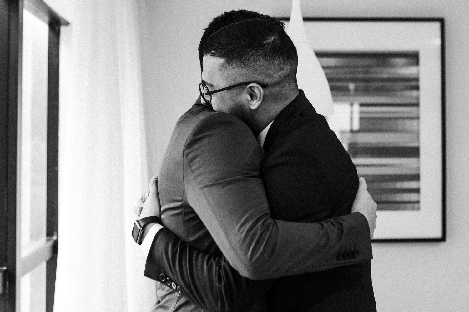 A series of black and white photographs on a wall show couples embracing in tender emotional moments.