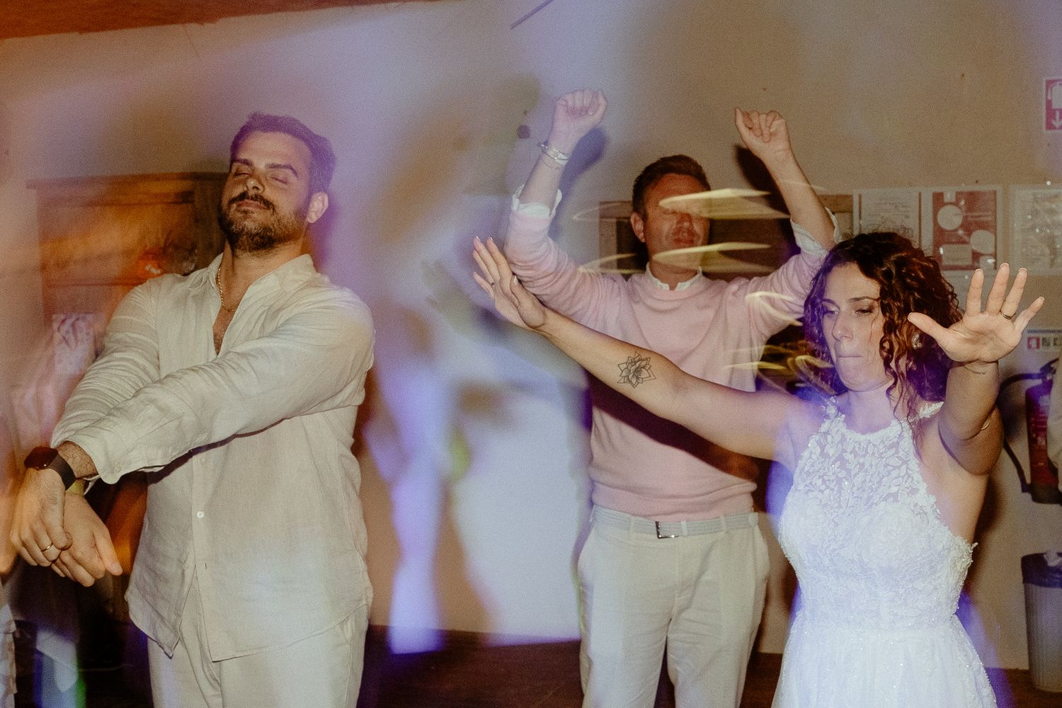 Bride and groom dancing energetically with guests at a wedding reception celebration.