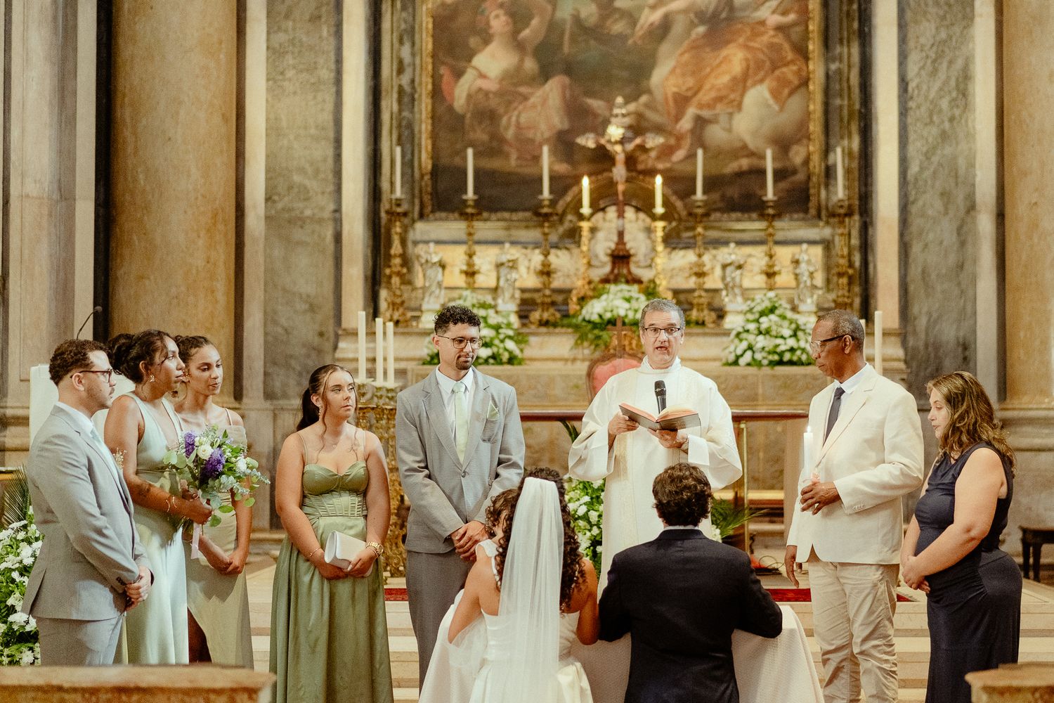 Elegant church wedding ceremony with bride, groom, and officiant at ornate altar surrounded by guests in formal attire.