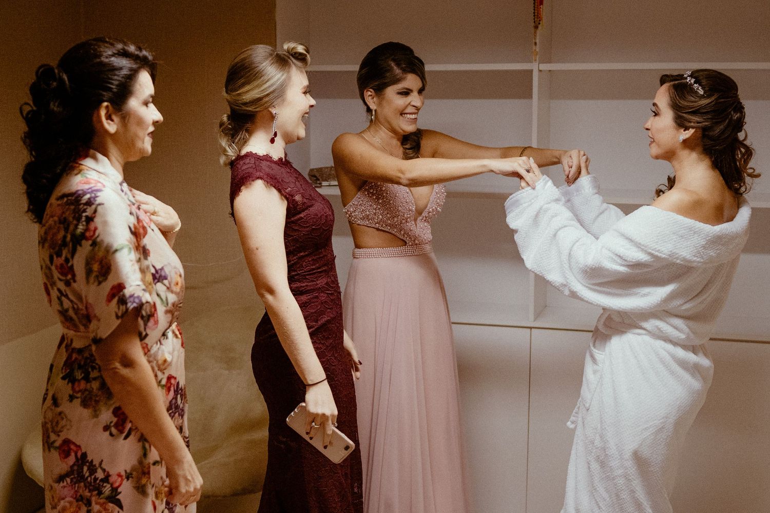 Joyful wedding party dances together in warm brown tones during a celebration.