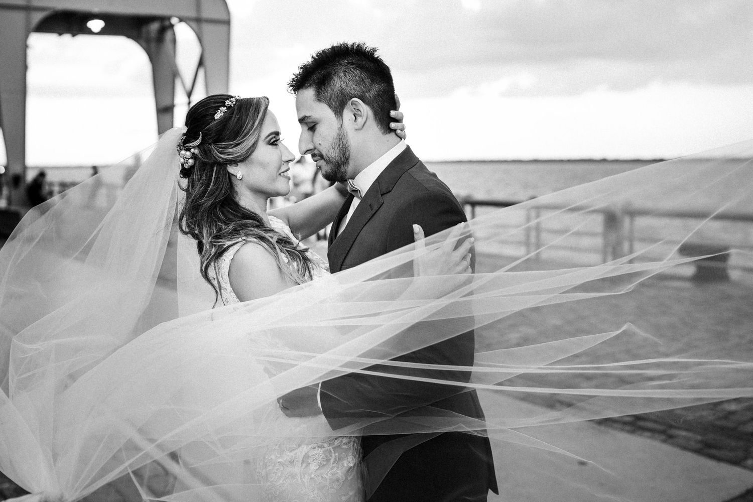 Romantic black and white wedding photos show tender moments between newlyweds against seaside backdrop.