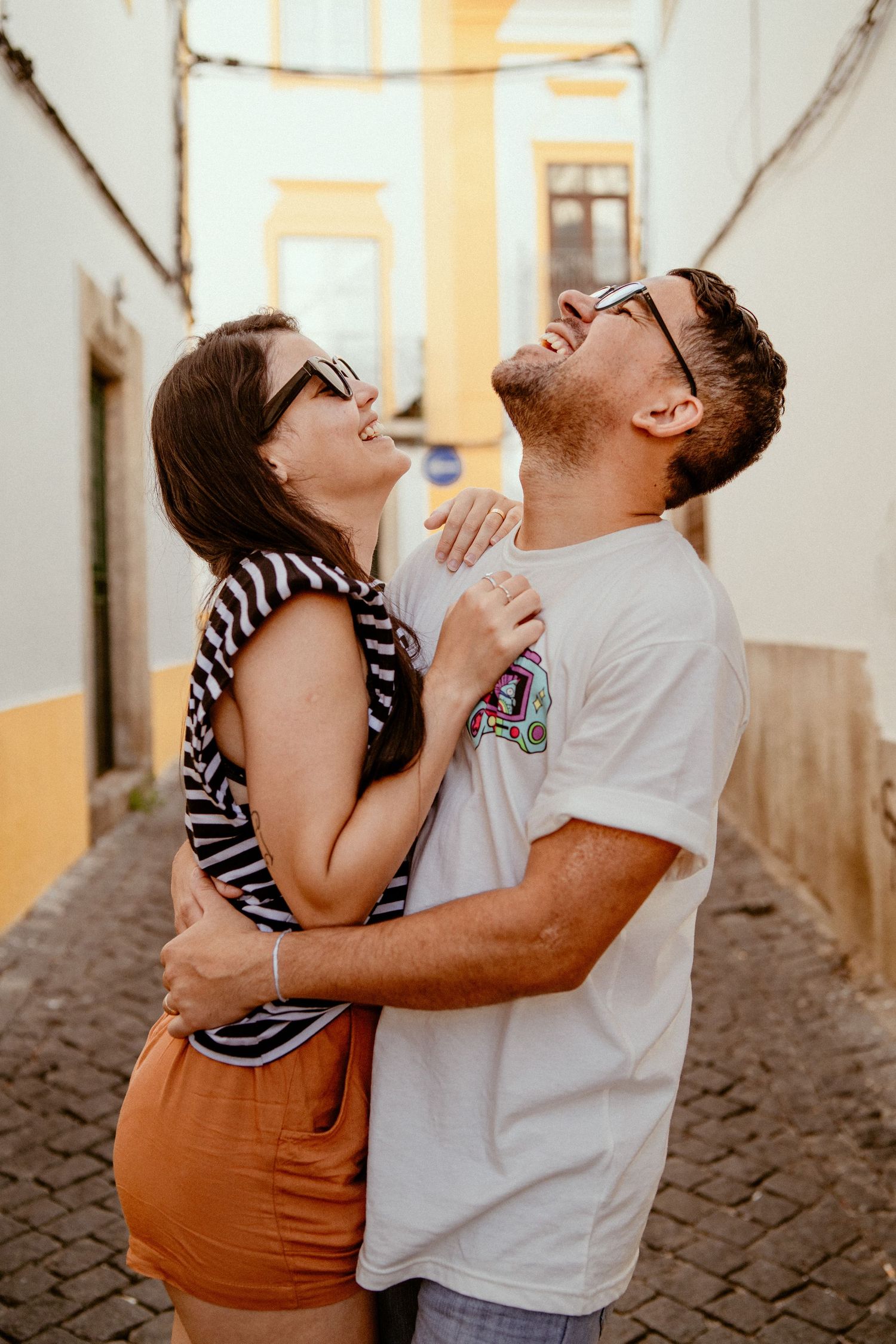 A couple sharing a joyful laughing moment together in a narrow European alley.
