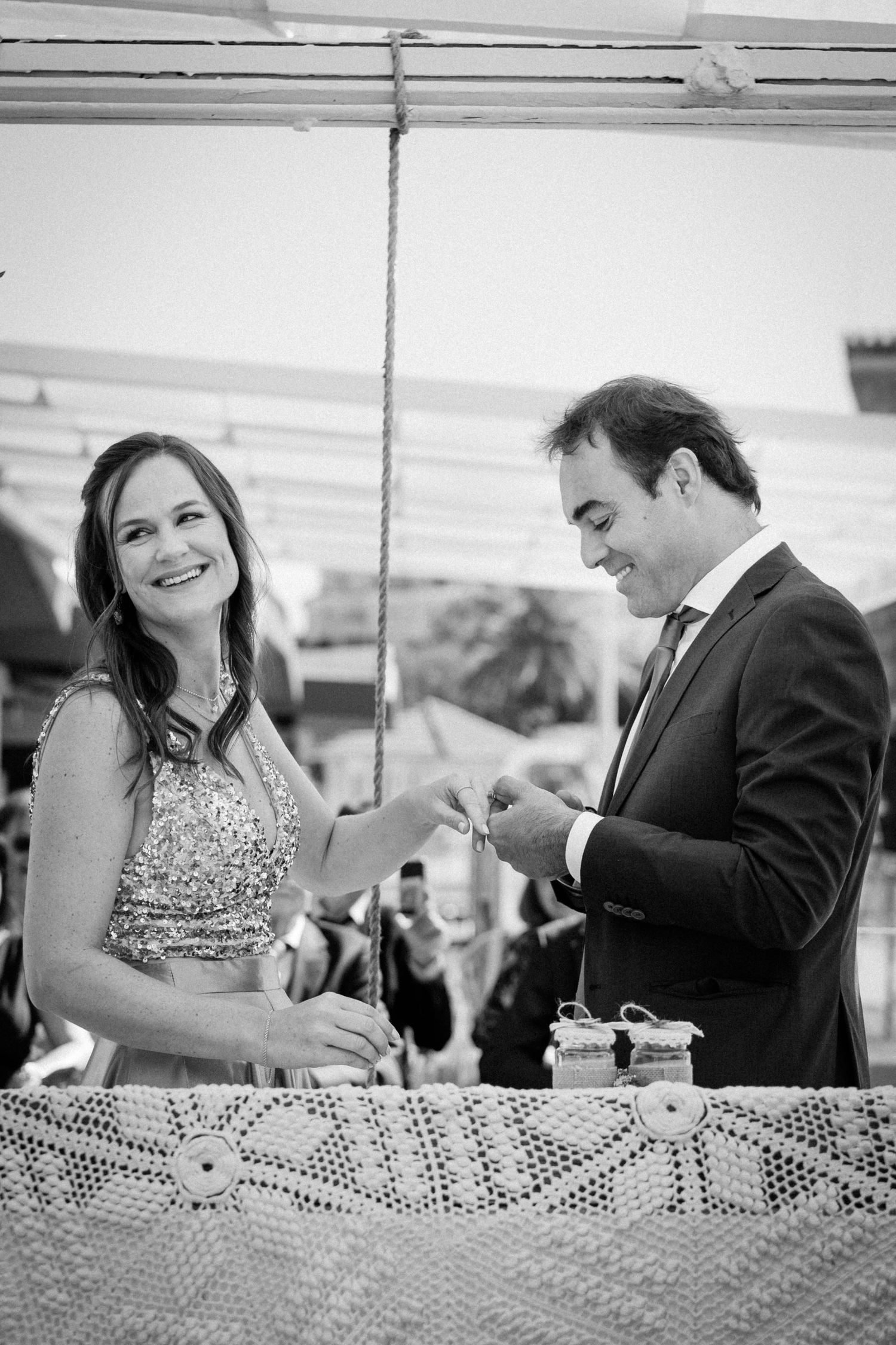 Black and white photo sequence showing a couple sharing a playful moment at an outdoor reception table.