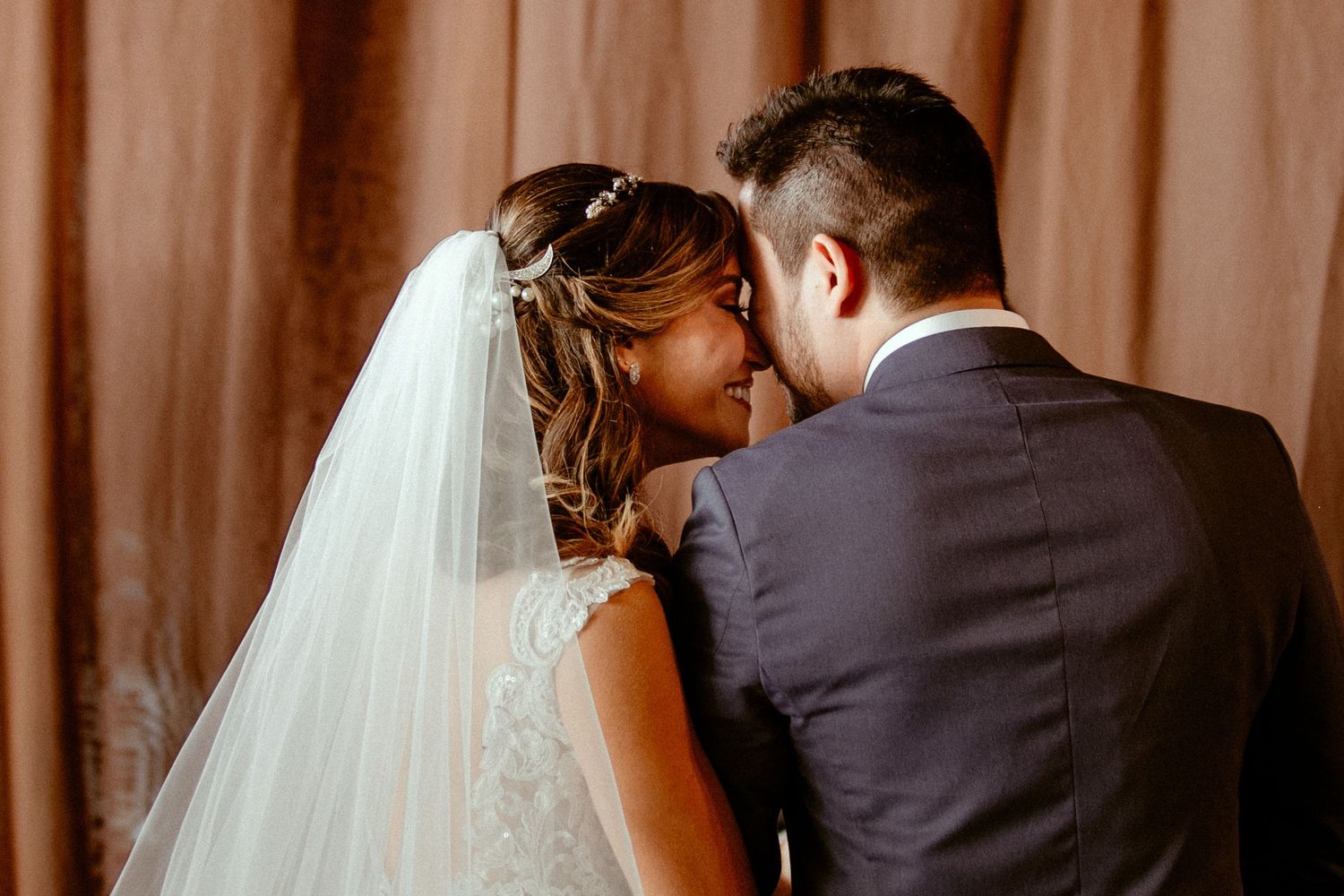 A romantic shot from behind couples dancing together with soft lighting at an intimate wedding reception.