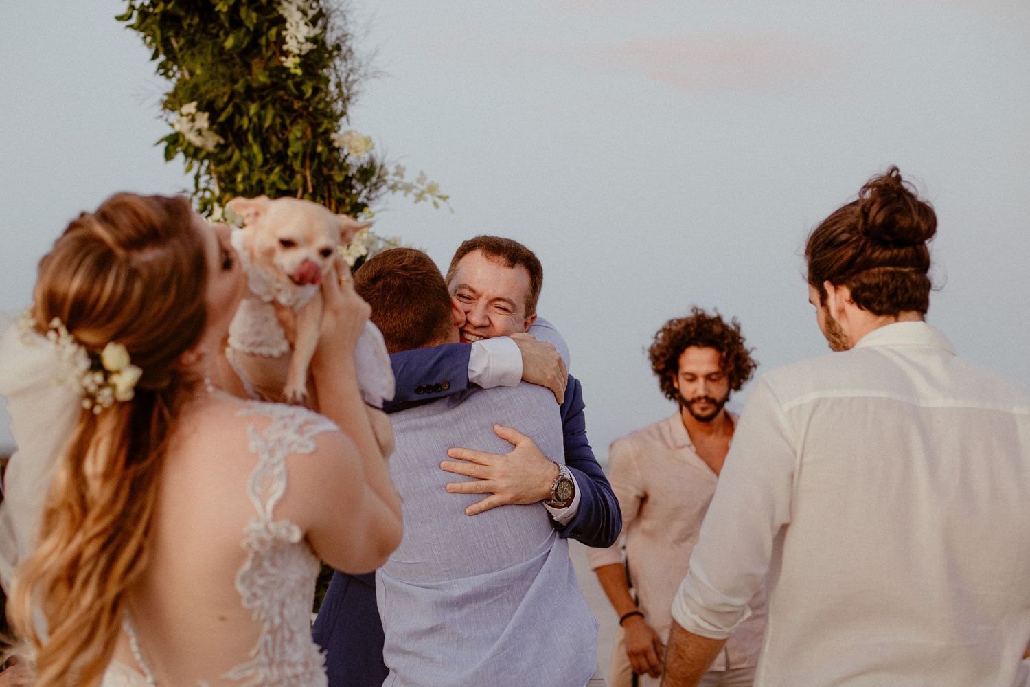 Celebratory wedding guests dance and mingle together during an outdoor reception at sunset.