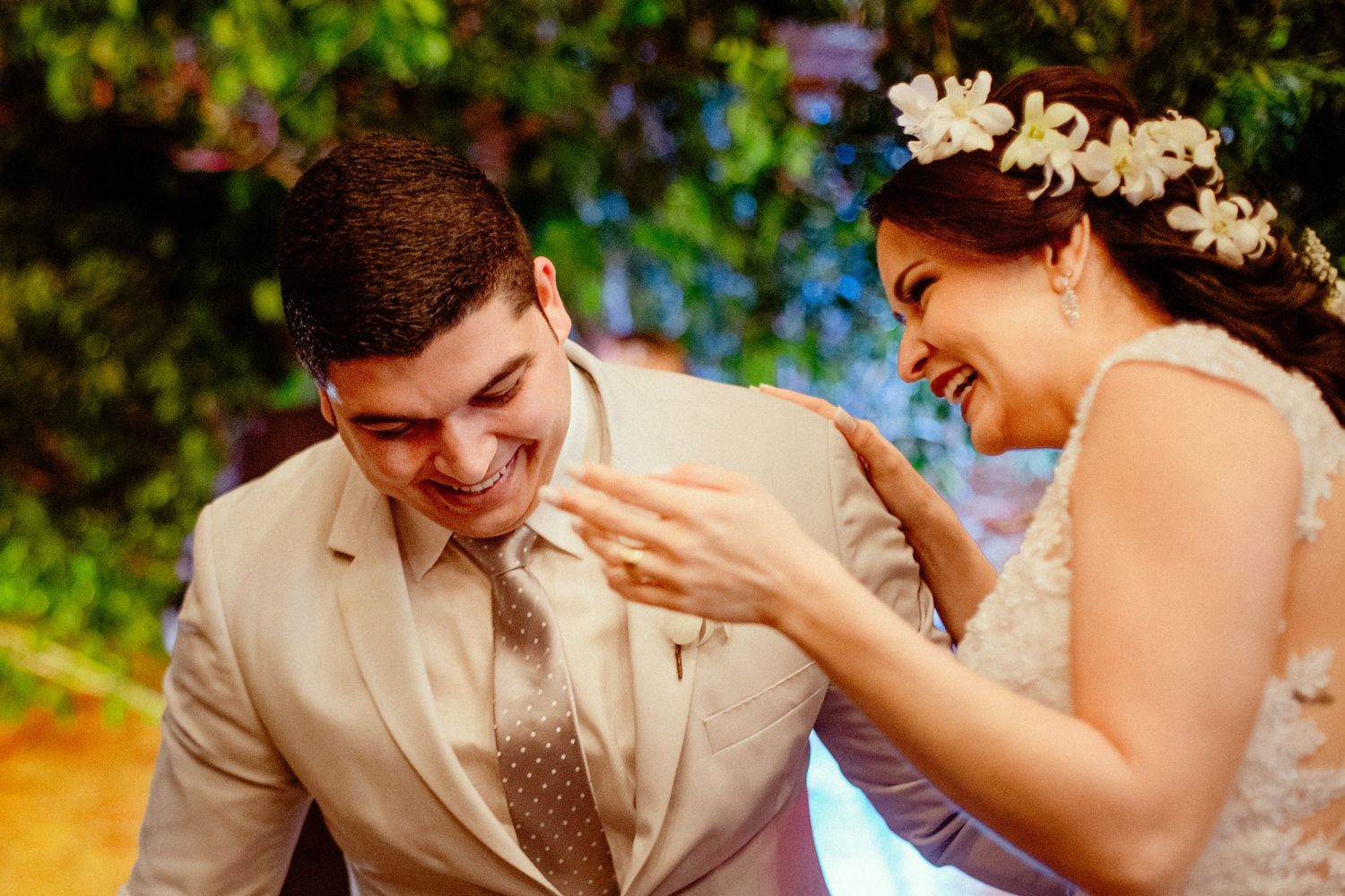 Candid moment of laughter between newlyweds in outdoor garden setting.