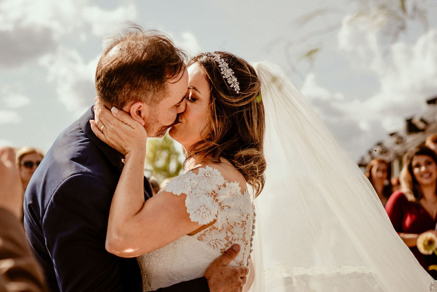 Intimate kiss between newlyweds during outdoor wedding ceremony.