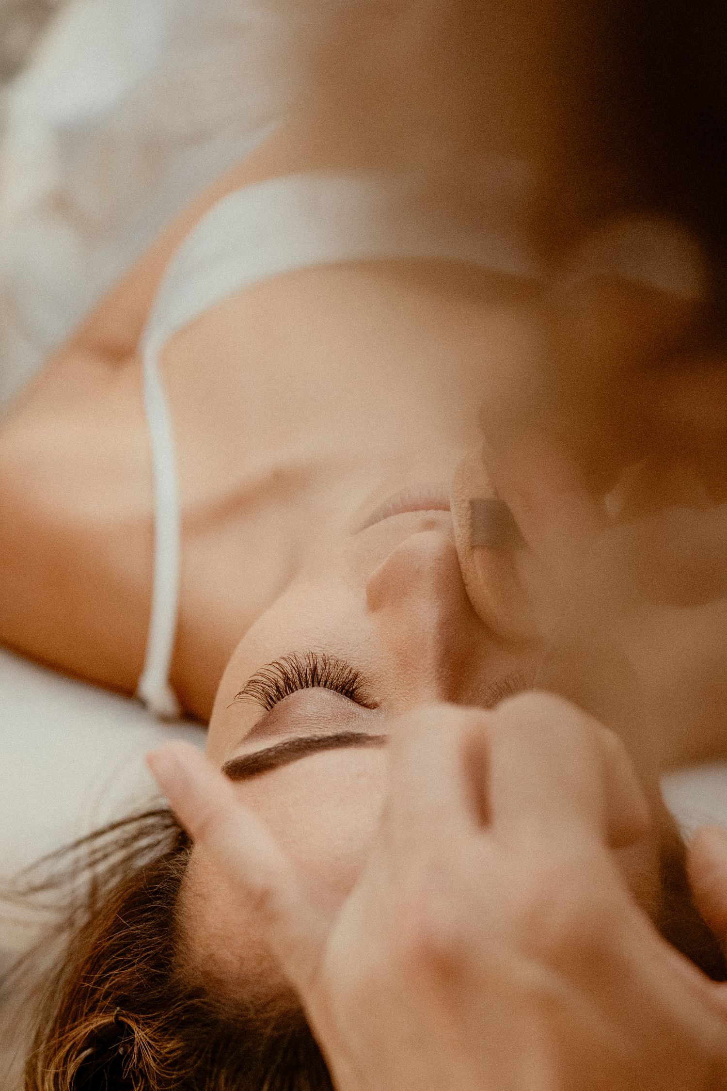 Close up photo with soft lighting showcases eyelashes and delicate features in a romantic, dreamlike composition.
