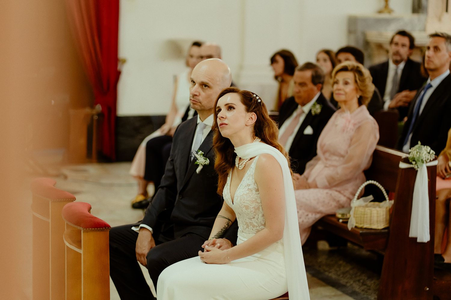 Bride and groom seated together during a church wedding ceremony, looking toward the altar.