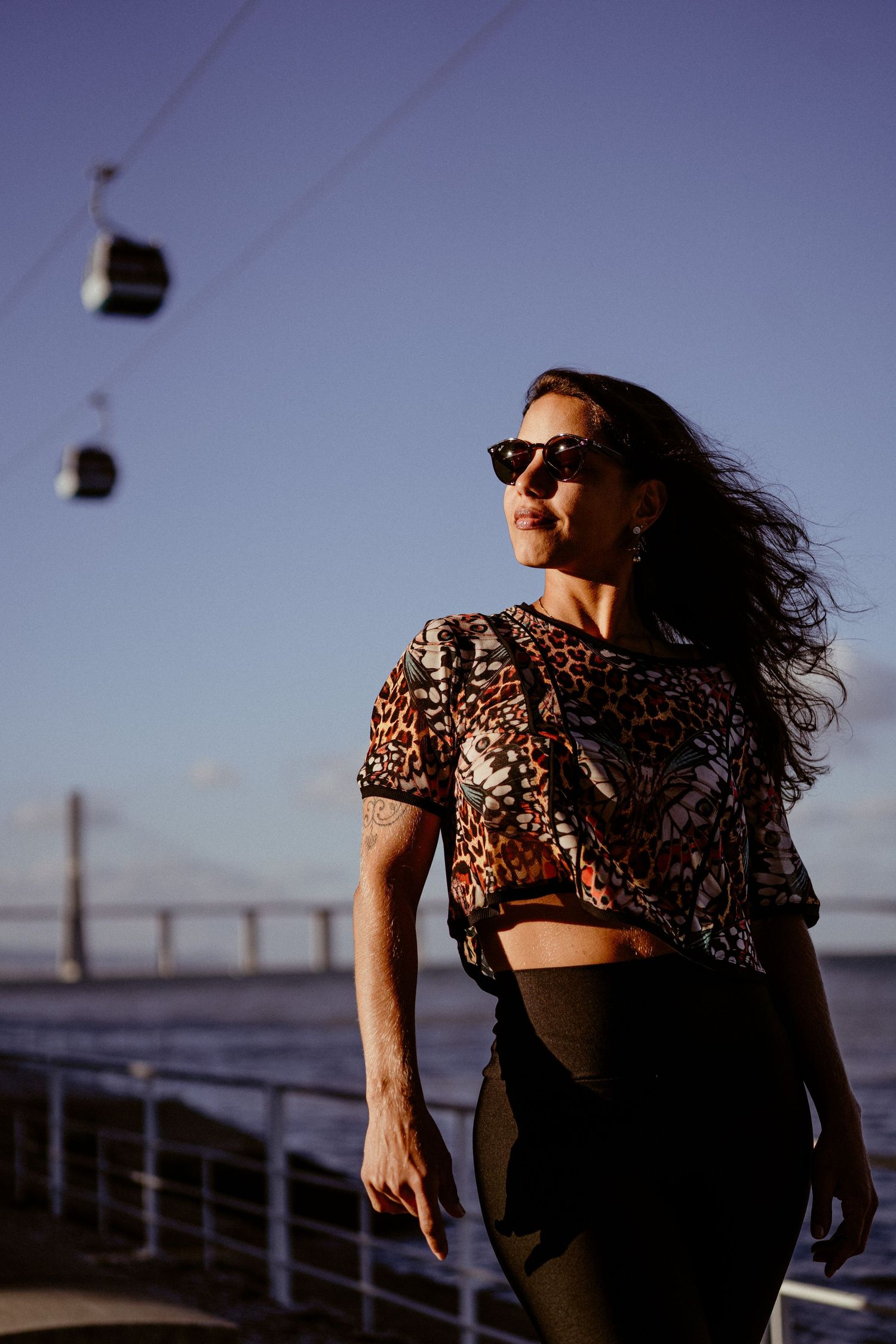 Person in leopard print top posing against seaside backdrop at sunset.