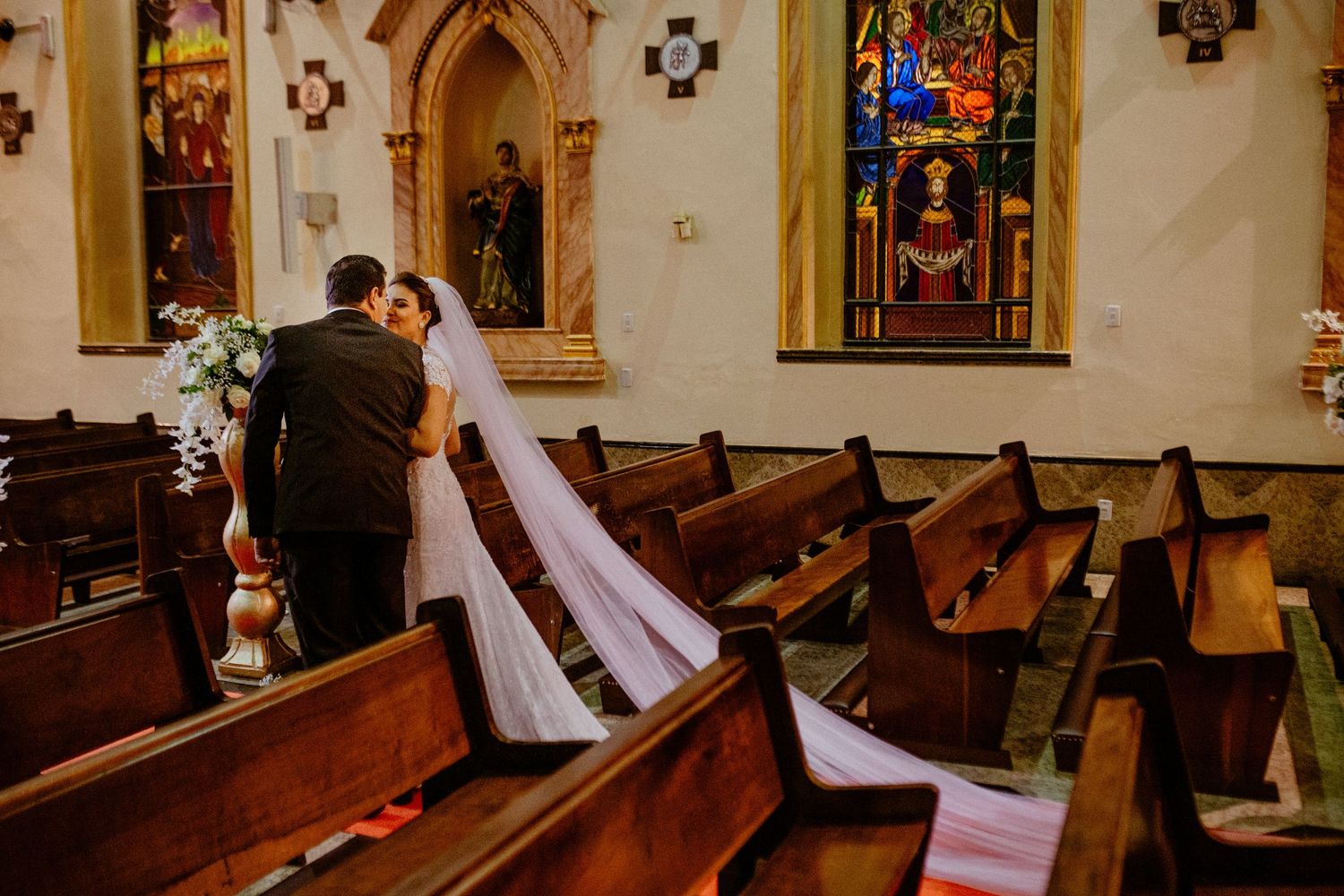 Wide angle view of traditional church interior with wooden pews and stained glass windows.