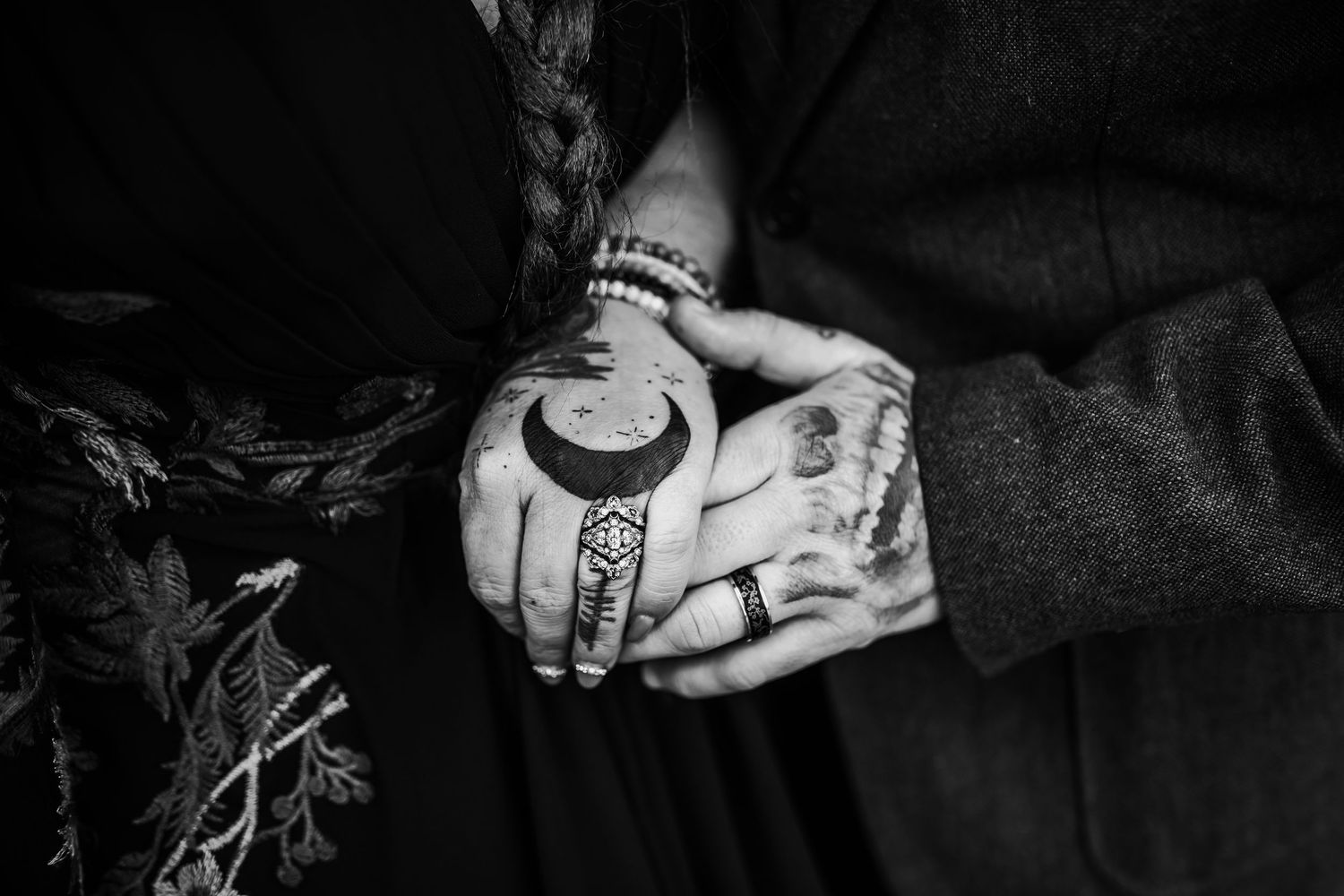 Two hands, displaying their wedding rings, are laid over top of one another.